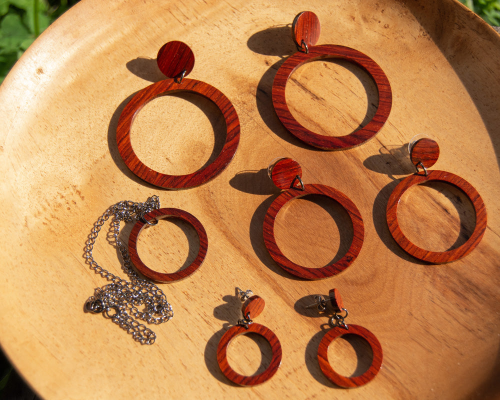 3 sizes of cocobolo wood hoops and necklace on wood plate 